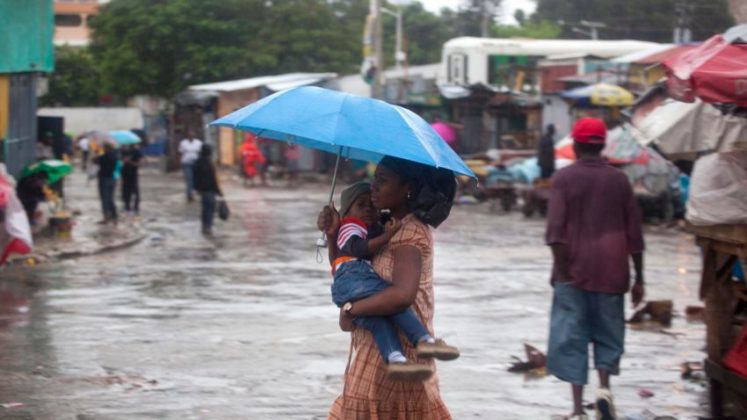 A woman carrying a child walks in the rain triggered by Hurricane Matthew in Port-au-Prince, Haiti, Tuesday, Oct. 4, 2016. Hurricane Matthew roared into the southwestern coast of Haiti on Tuesday, threatening a largely rural corner of the impoverished country with devastating storm conditions as it headed north toward Cuba and the eastern coast of Florida. (AP Photo/Dieu Nalio Chery)