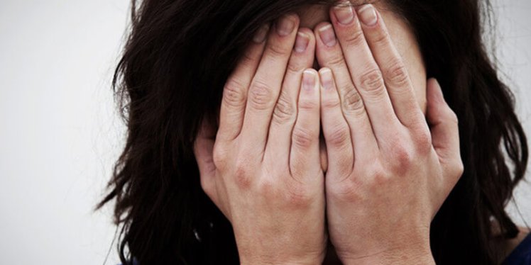 woman in pain covering her face